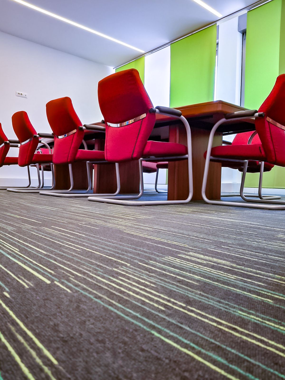 Sala riunioni con sedie rosse su moquette pulita